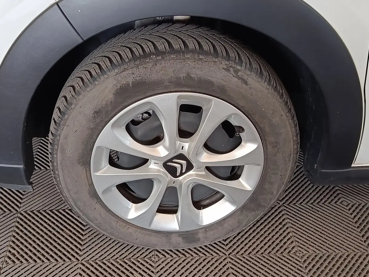 Gros plan sur la roue avant droite d'une Citroën C3 blanche, mettant en valeur la jante en alliage argentée.