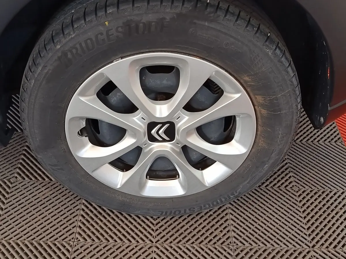 Gros plan sur la roue avant gauche d'une Citroën C3 blanche avec jante argentée et logo Citroën au centre.