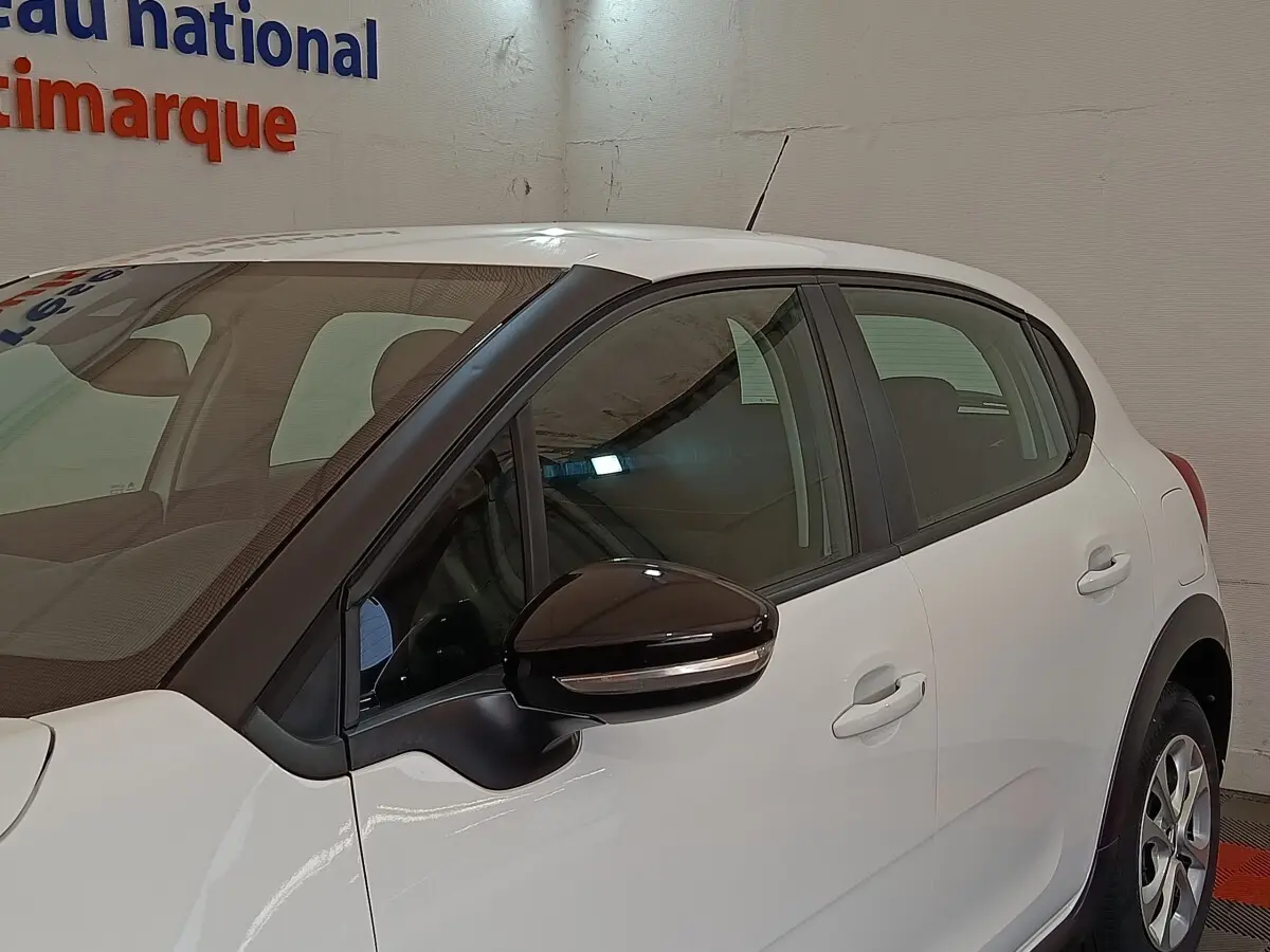 Vue latérale droite d'une Citroën C3 blanche 2020 avec rétroviseur noir et poignées de porte ton caisse.