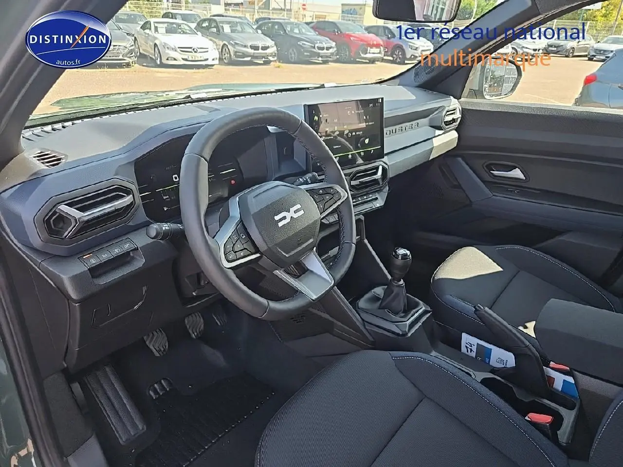 Intérieur avant du Dacia Duster 2025 vert kaki, volant multifonction et écran tactile au centre du tableau de bord.