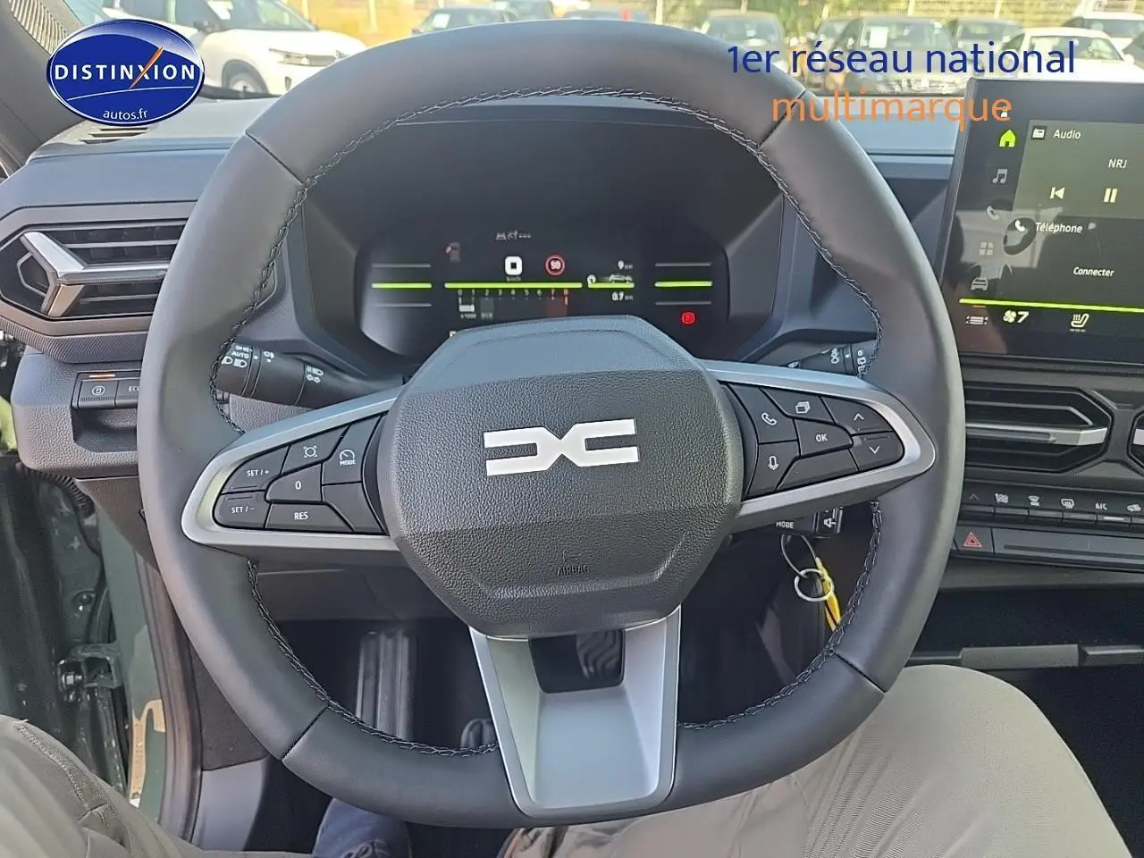 Vue intérieure centrée sur le volant multifonction noir du Dacia Duster 2025 avec tableau de bord digital et écran tactile.