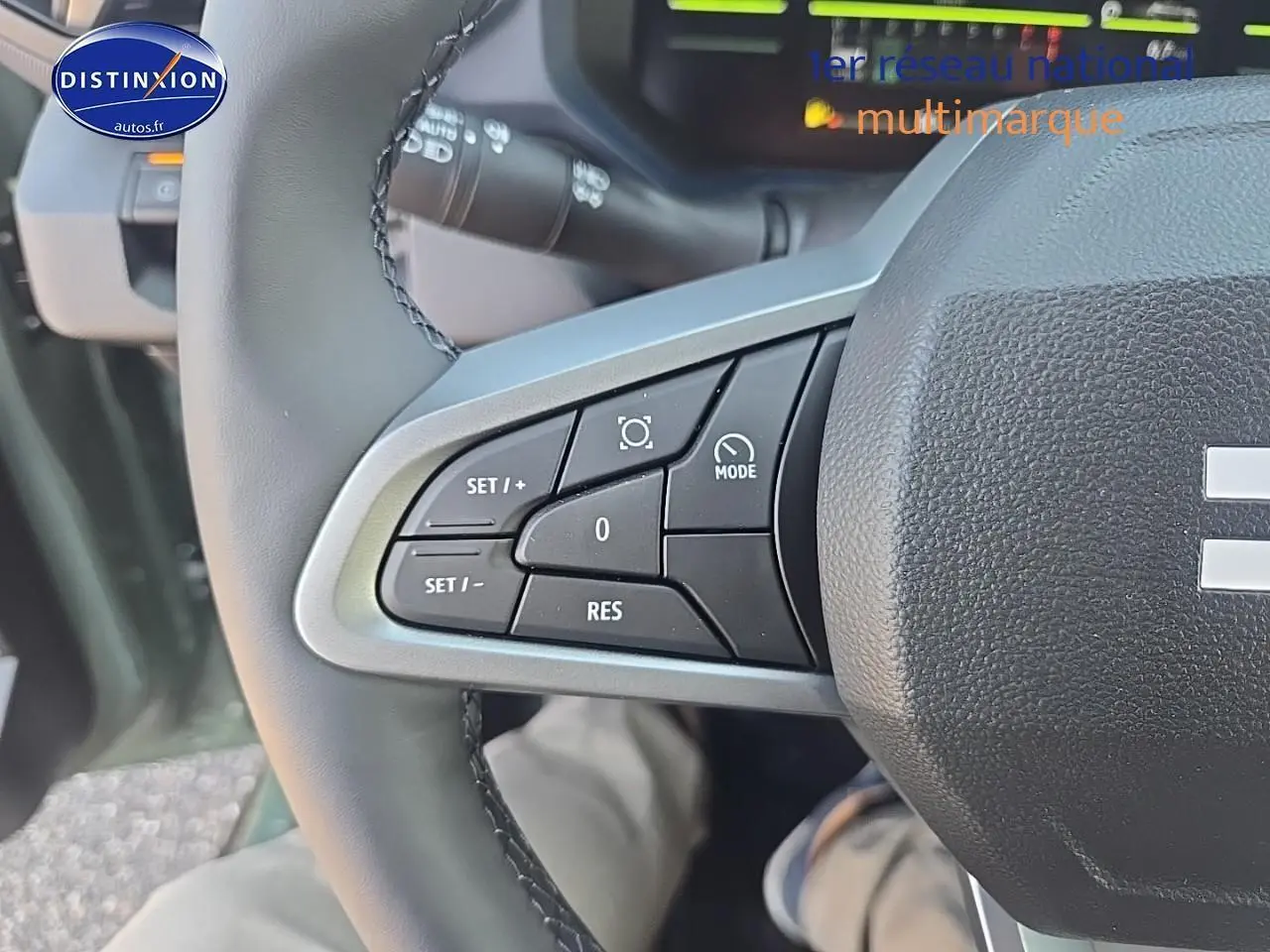 Gros plan sur les commandes à gauche du volant du Dacia Duster vert kaki 2025, montrant les boutons de régulateur de vitesse.