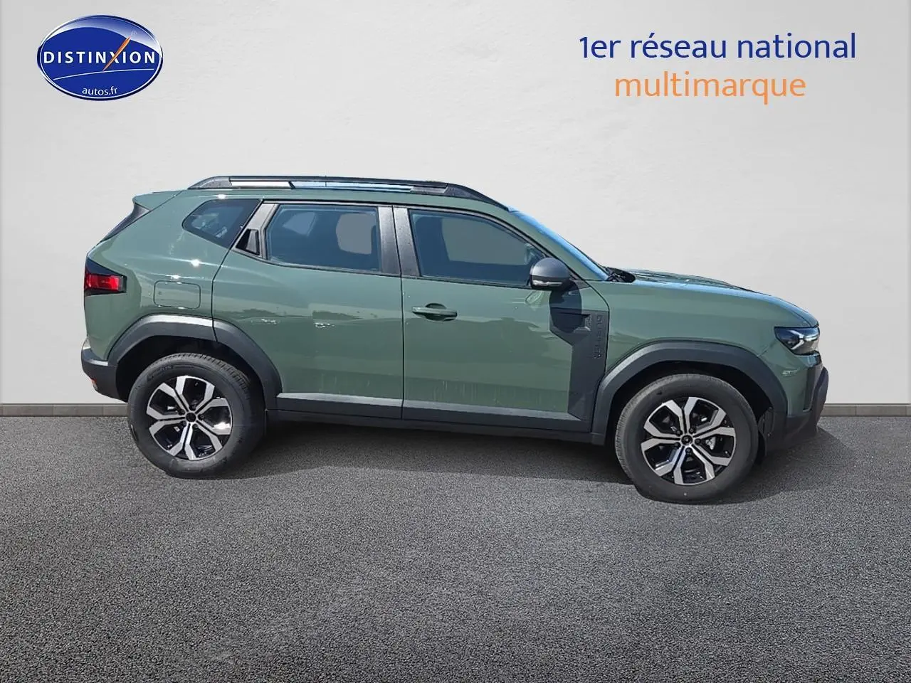 Profil droit d'un Dacia Duster 2025 vert kaki avec barres de toit et jantes alliage noir et argent.