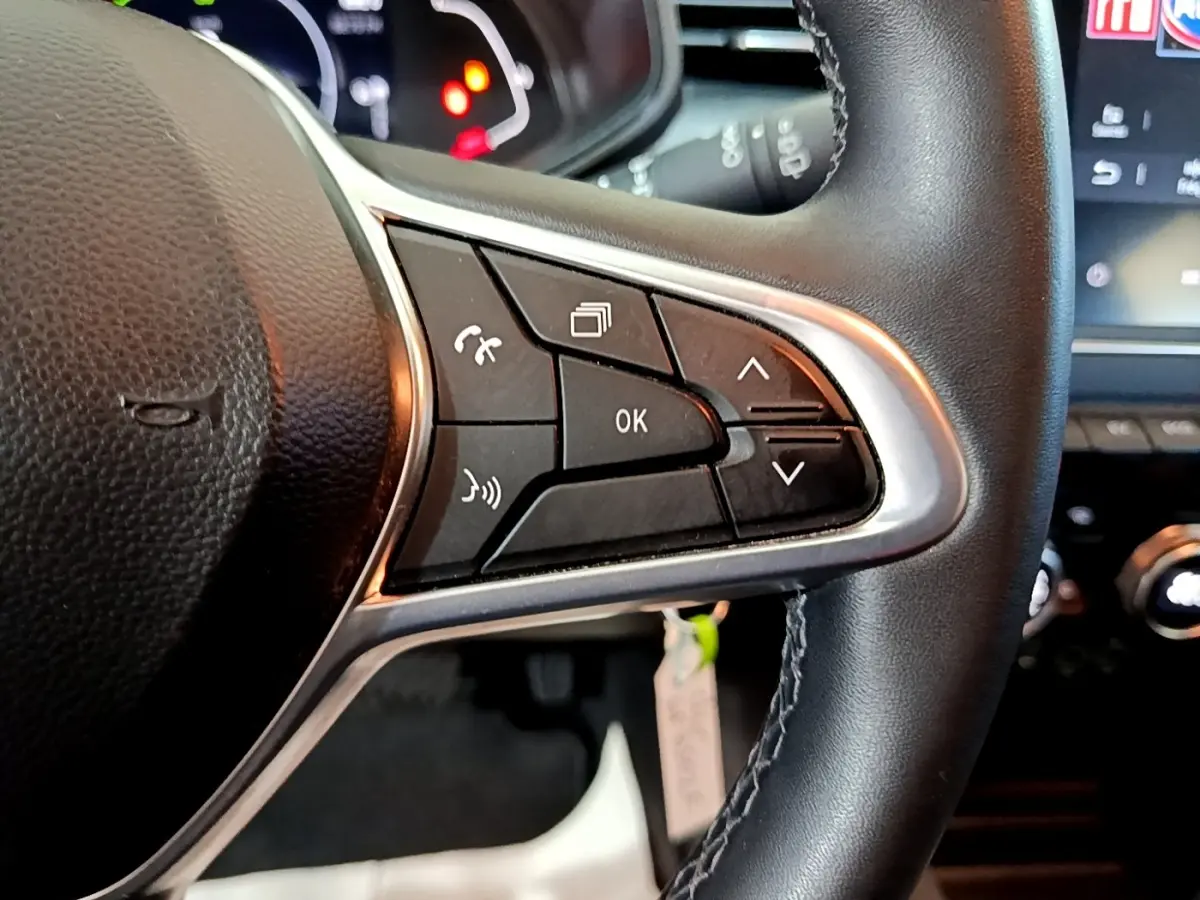 Gros plan sur les commandes multifonctions du volant en cuir noir de la Renault Clio Business E-TECH 140 gris foncé, 2022.