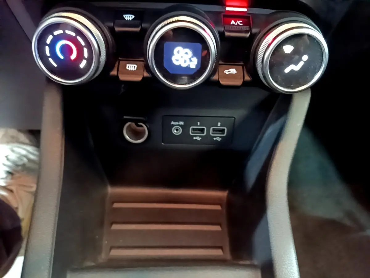 Gros plan sur la console centrale de la Renault Clio Business E-TECH 140, avec commandes de climatisation et ports USB visibles.