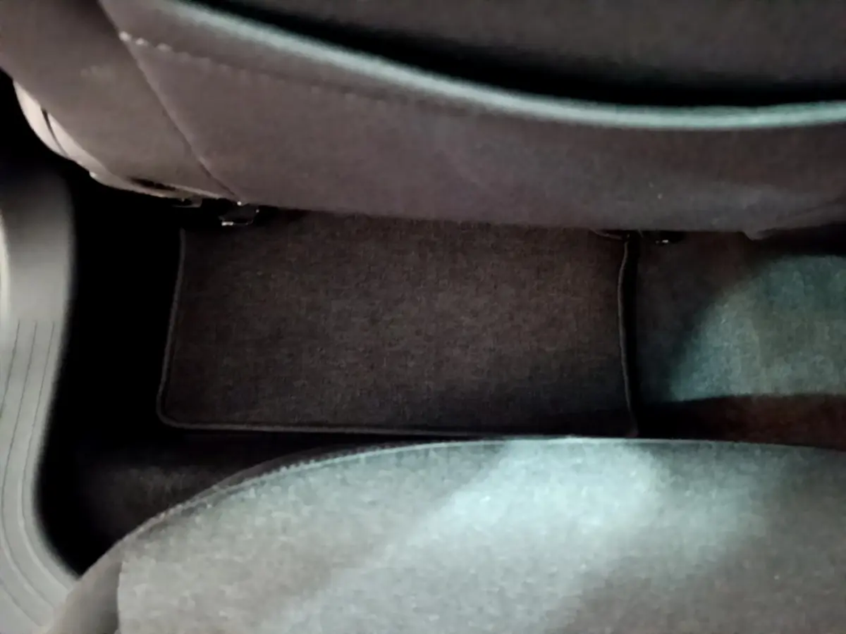 Vue rapprochée du sol côté passager arrière d’une Renault Clio Business E-TECH 140 gris foncé, tapis de sol visible.