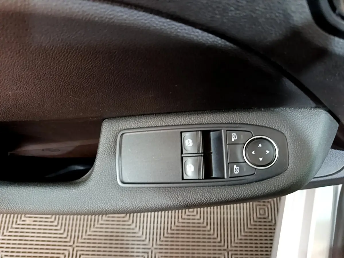 Commande des vitres électriques et réglage des rétroviseurs sur la portière côté conducteur d'une Renault Clio gris foncé.