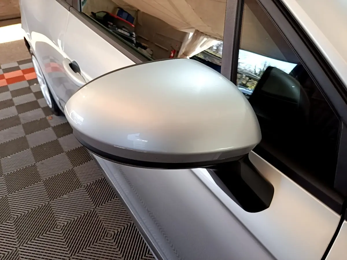 Gros plan sur le rétroviseur droit gris clair de la Renault Clio Business E-TECH 140, avec partie de la porte blanche visible.