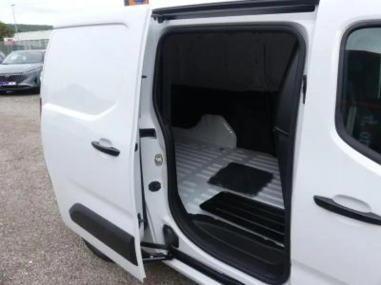 Vue côté droit en plan rapproché du Peugeot Partner XL blanc avec porte latérale ouverte montrant l’espace de chargement vide.