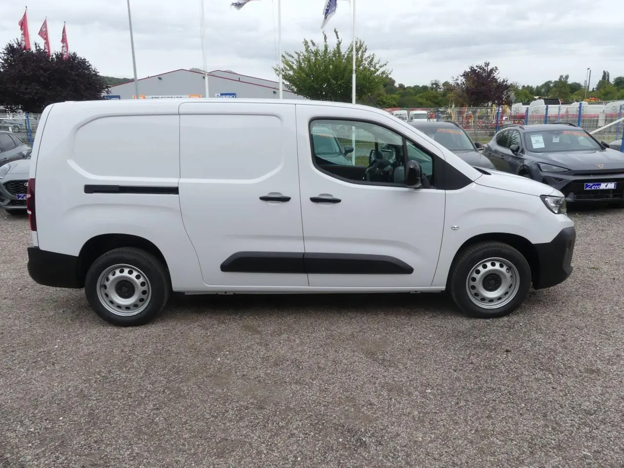Vue de profil côté droit d'un utilitaire Peugeot Partner blanc avec porte latérale coulissante et jantes tôles grises.