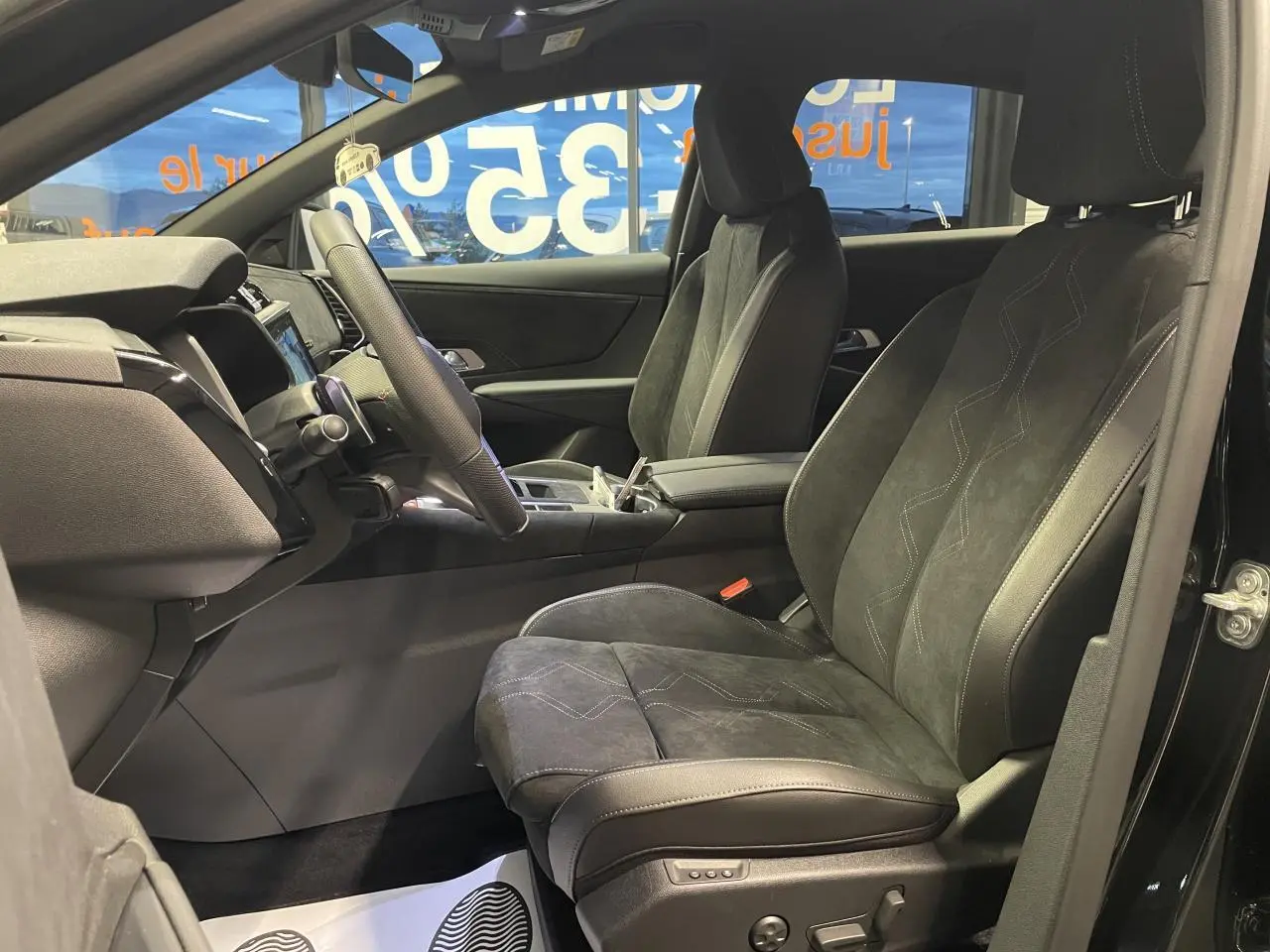 Vue intérieure côté conducteur du DS7 Crossback noir métallisé, sièges Alcantara noirs avec surpiqûres et console centrale visible.