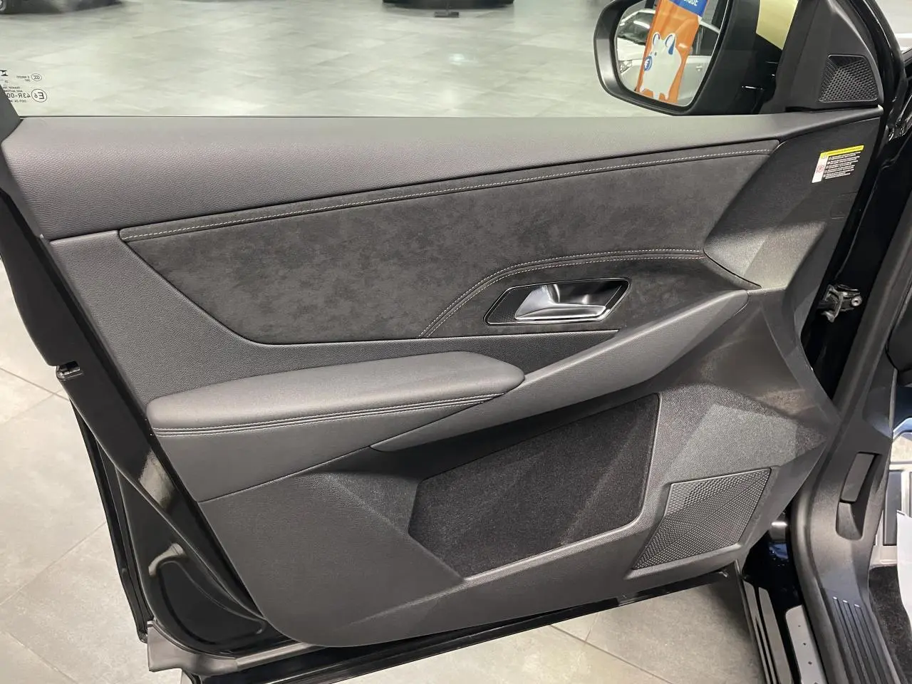 Vue intérieure côté gauche de la porte avant d’un DS7 Crossback noir métallisé avec garniture Alcantara et surpiqûres.