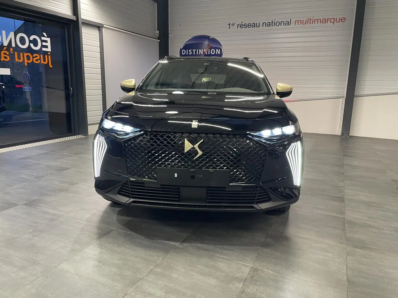 Vue avant d'un DS7 Crossback noir métallisé avec calandre DS Wings et feux LED verticaux allumés en showroom.