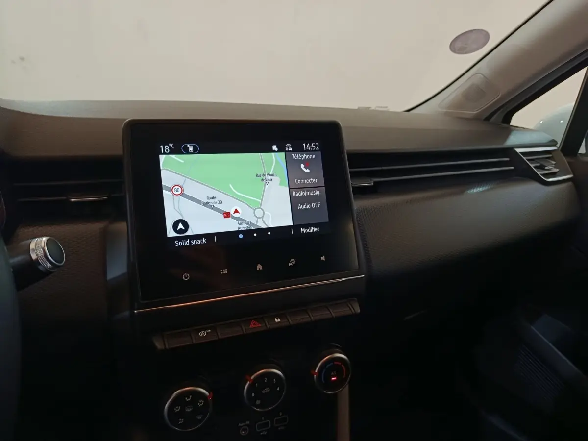 Vue intérieure du tableau de bord de la Renault Clio Business blanc, avec écran tactile de navigation affiché.