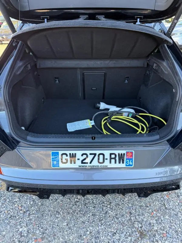 Coffre ouvert vu de l'arrière d'une CUPRA Formentor noir 2024 avec câble de recharge hybride visible.