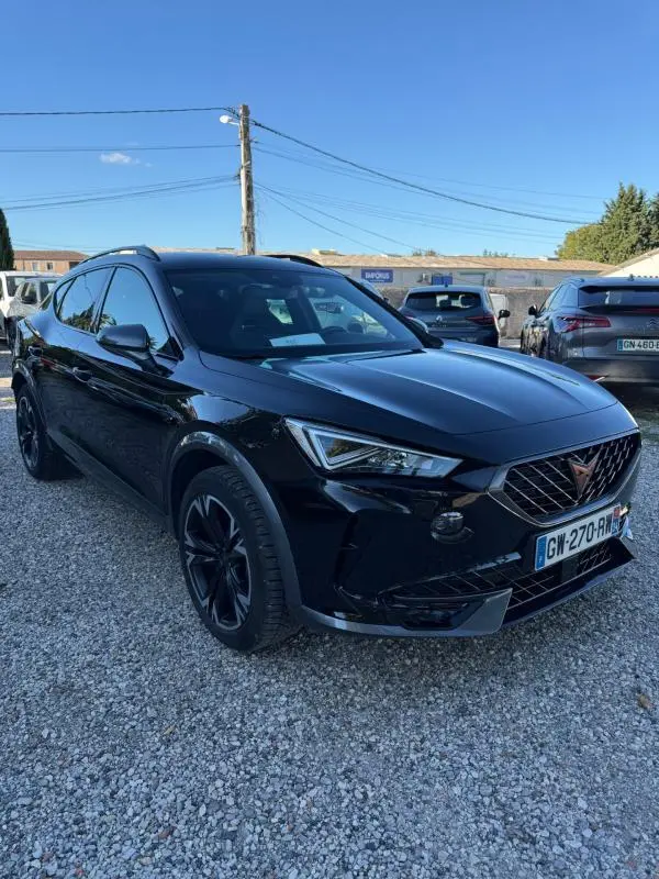 SUV CUPRA Formentor noir en 3/4 avant droit, avec calandre distinctive et jantes noires, stationné sur un sol gravillonné.