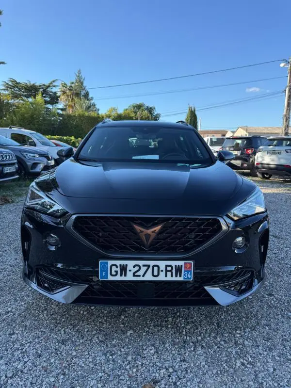 Vue avant d'un CUPRA Formentor noir 2024 avec calandre noire et logo cuivre, sur un parking extérieur ensoleillé.