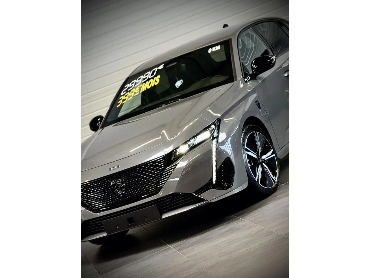 Vue 3/4 avant droit de la Peugeot 308 gris sélénium avec calandre noire brillante et jantes alliage 18 pouces.