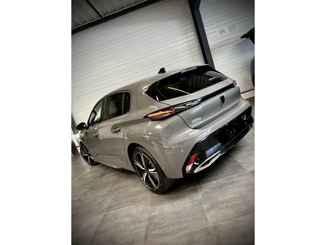 Vue 3/4 arrière droite de la Peugeot 308 GT gris selenium avec feux arrière à signature lumineuse et jantes alliage 18 pouces.