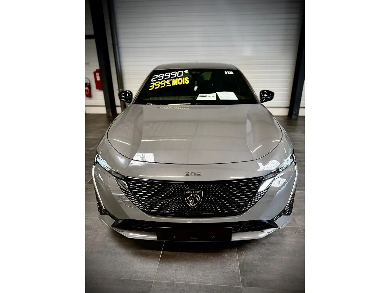Vue avant centrale d'une Peugeot 308 gris sélénium avec calandre noire brillante et feux LED distinctifs.