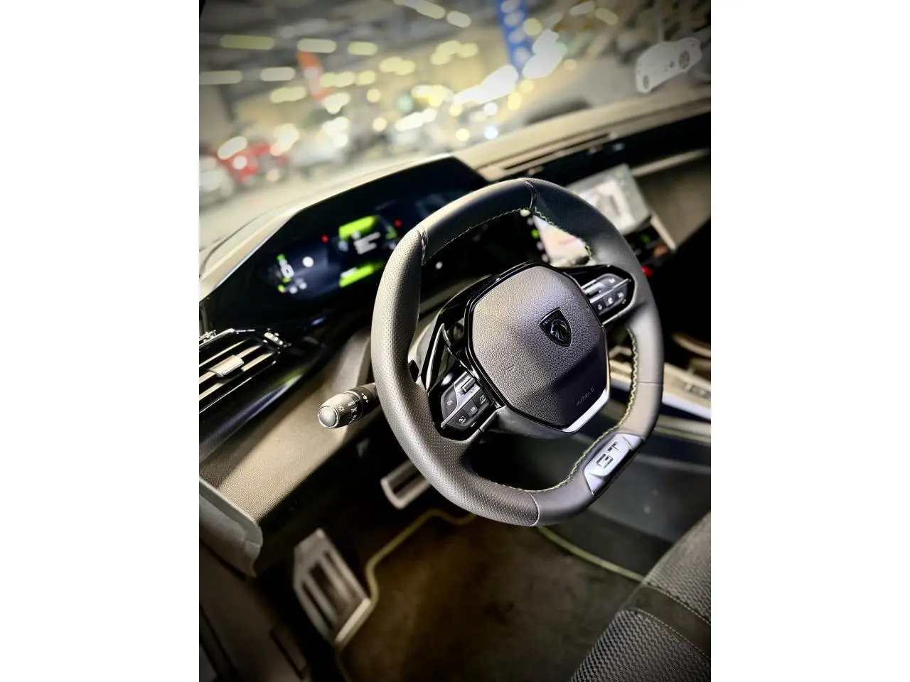 Vue intérieure rapprochée du volant cuir GT et du combiné numérique de la Peugeot 308 gris selenium 2025.