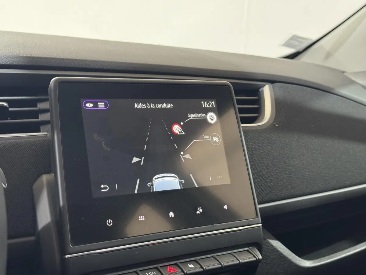 Écran tactile central affichant les aides à la conduite dans l'habitacle noir de la Renault ZOE blanche de 2020.