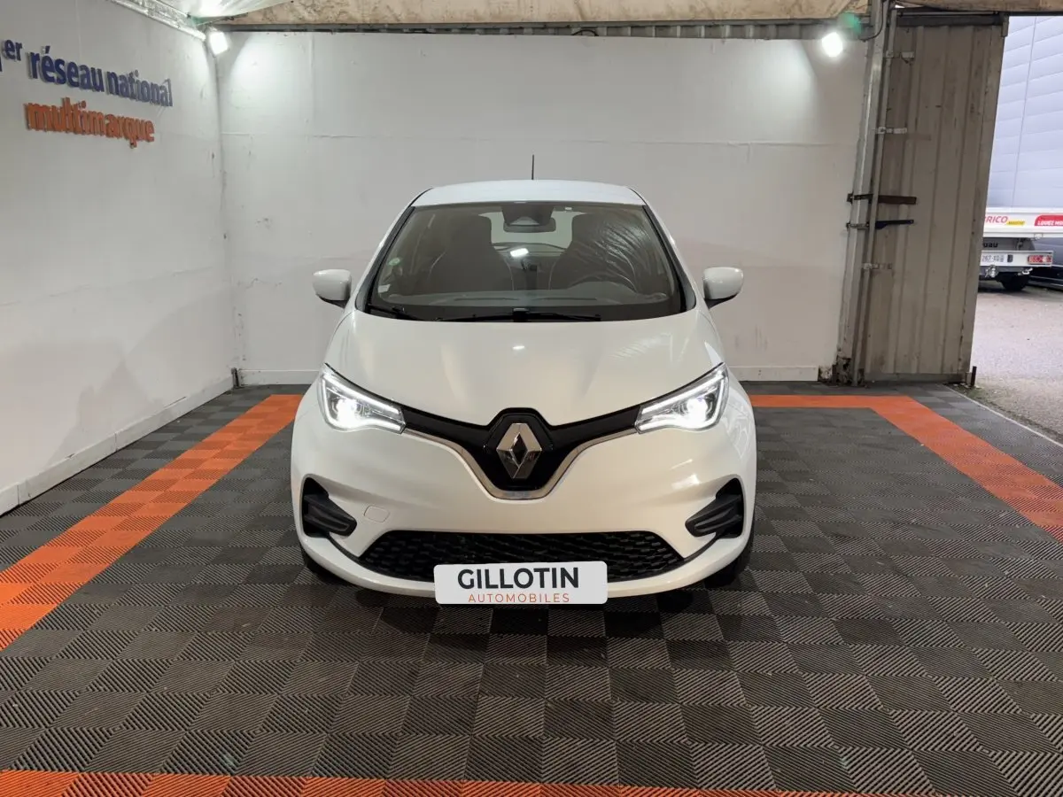 Vue frontale d'une Renault ZOE blanche 2020 avec phares LED allumés dans un garage.