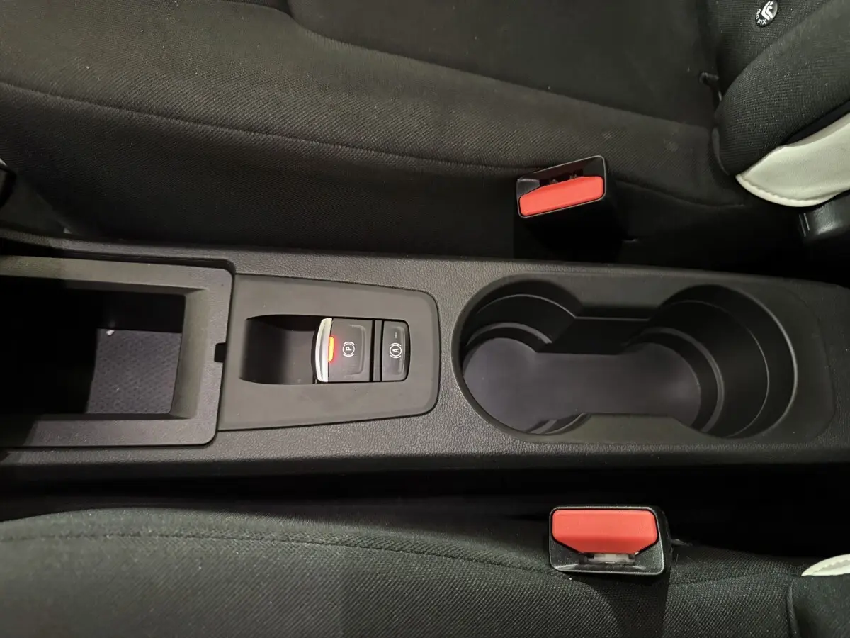 Vue rapprochée de la console centrale noire avec frein à main électrique et porte-gobelets de la Renault ZOE blanche 2020.