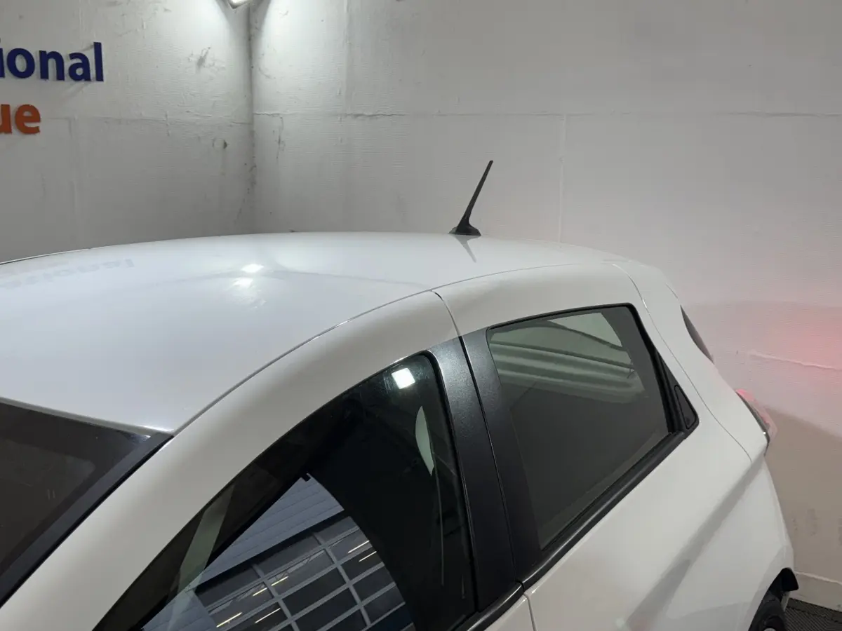 Vue 3/4 arrière droite d'une Renault ZOE Business blanche de 2020 avec antenne de toit et vitres teintées.