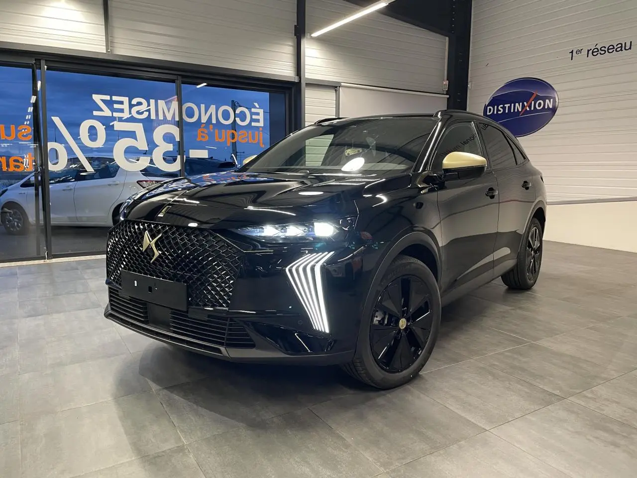 DS7 Crossback noir métallisé en 3/4 avant droit, avec calandre DS Wings et rétroviseurs couleur crème visibles en intérieur showroom.