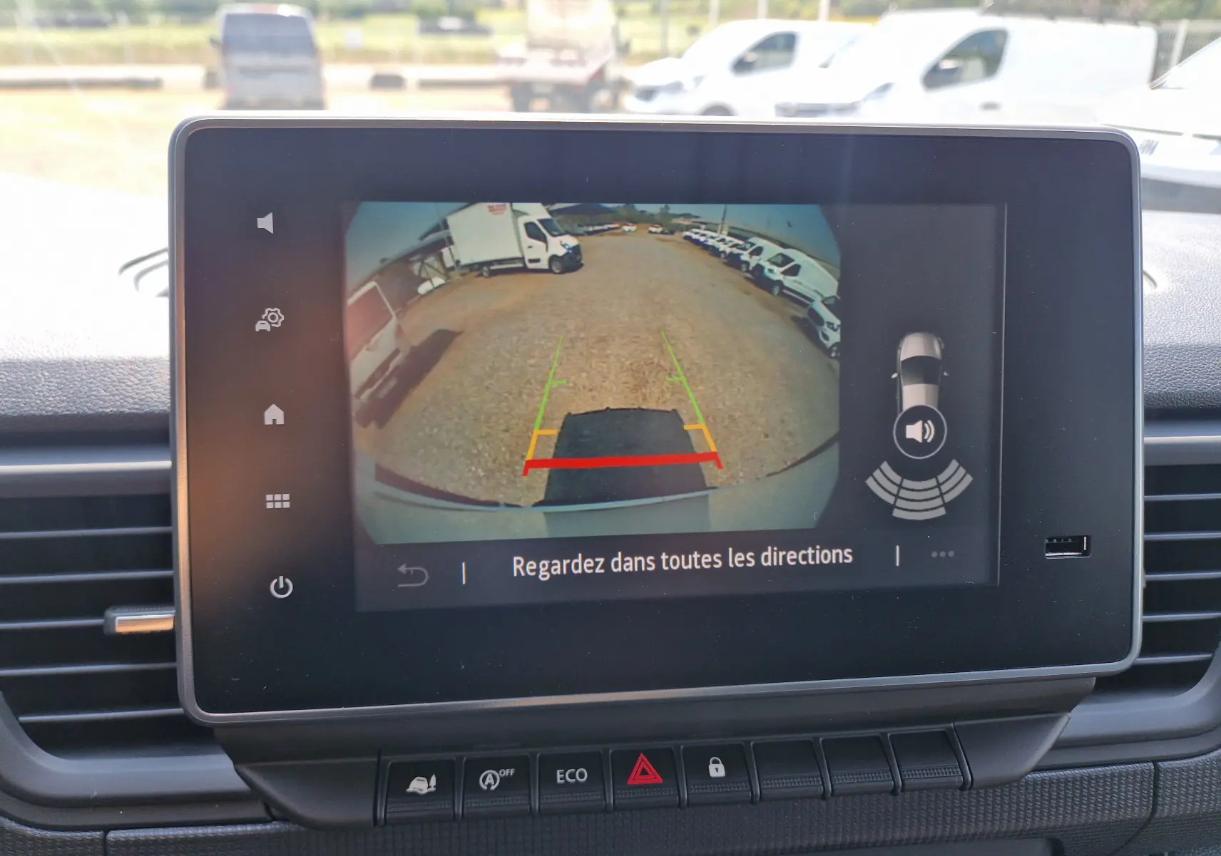 Écran tactile montrant la caméra de recul du Renault Trafic blanc, vue arrière avec lignes de guidage colorées.