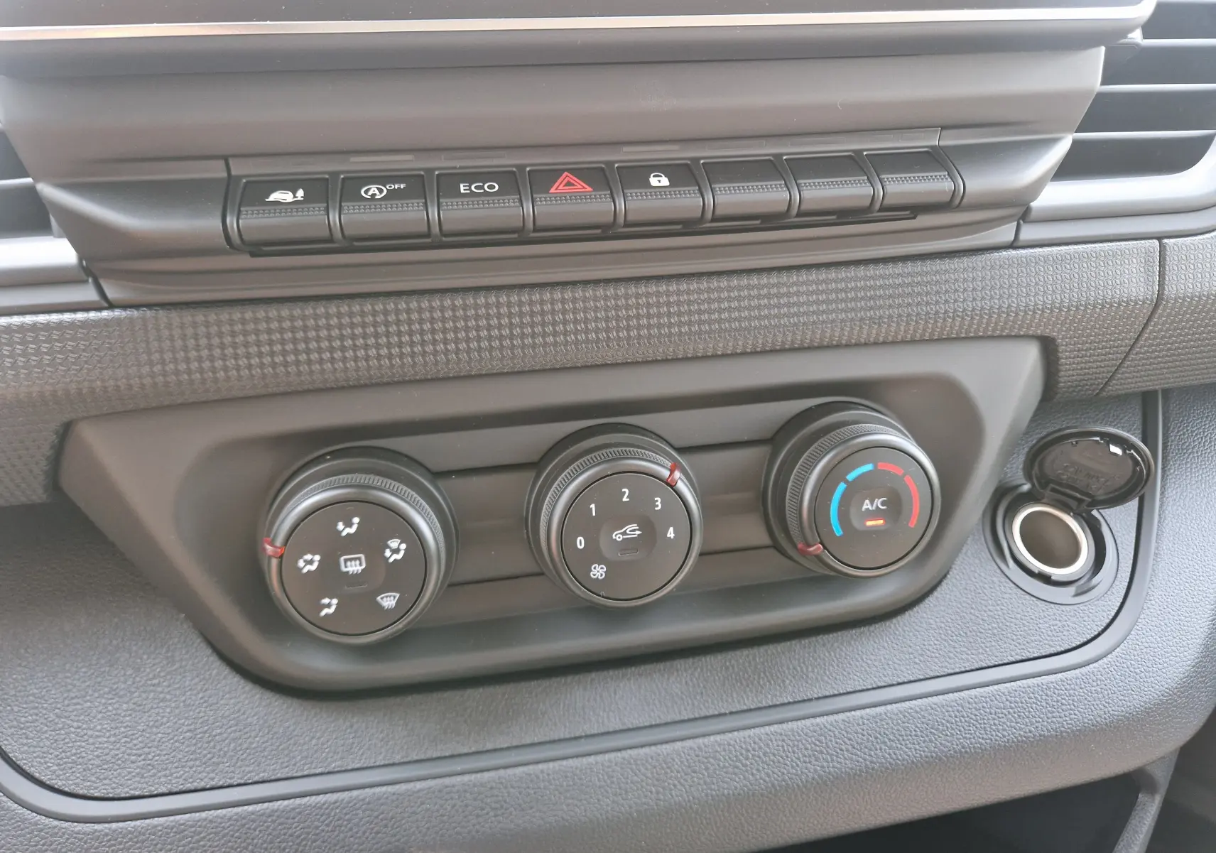 Gros plan sur les commandes de climatisation et boutons de fonction du tableau de bord du Renault Trafic Fourgon blanc 2026.