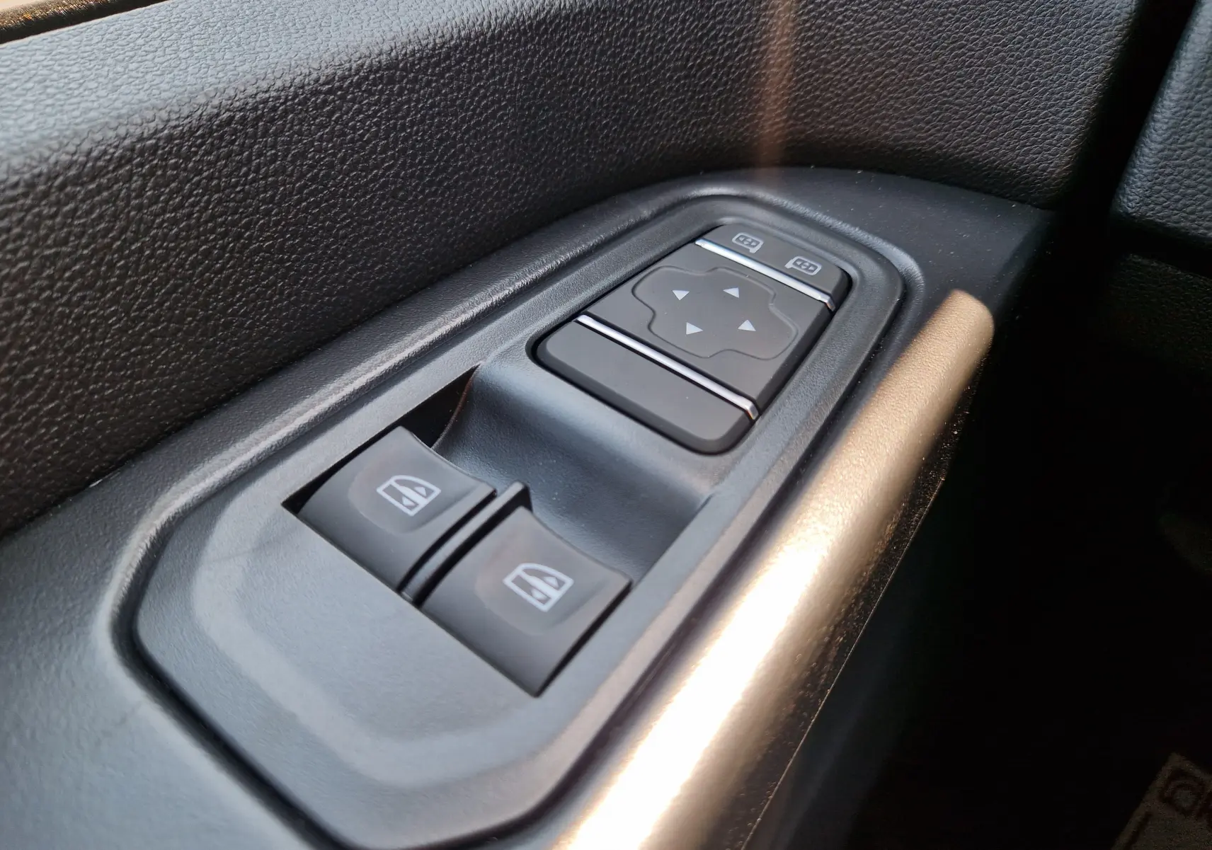 Gros plan sur les commandes de lève-vitres et réglage des rétroviseurs côté conducteur du Renault Trafic Fourgon blanc 2026.