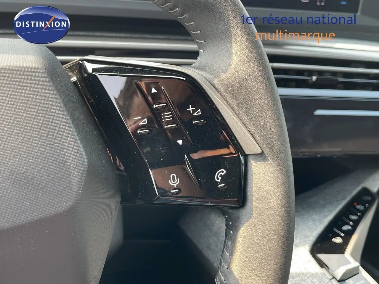 Gros plan sur les commandes gauche du volant cuir noir du Peugeot 3008 Hybrid gris Artense, avec tableau de bord en arrière-plan.