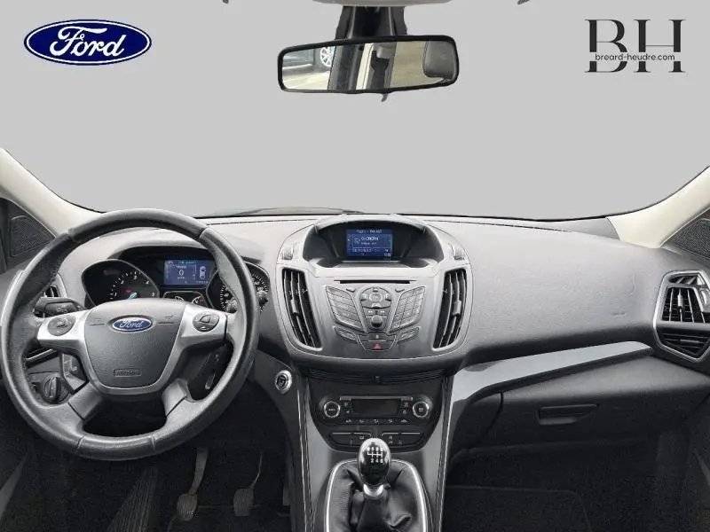 Vue intérieure avant du Ford Kuga 2.0 TDCi 150ch Titanium 2015, tableau de bord noir avec volant cuir multifonction et écran central.