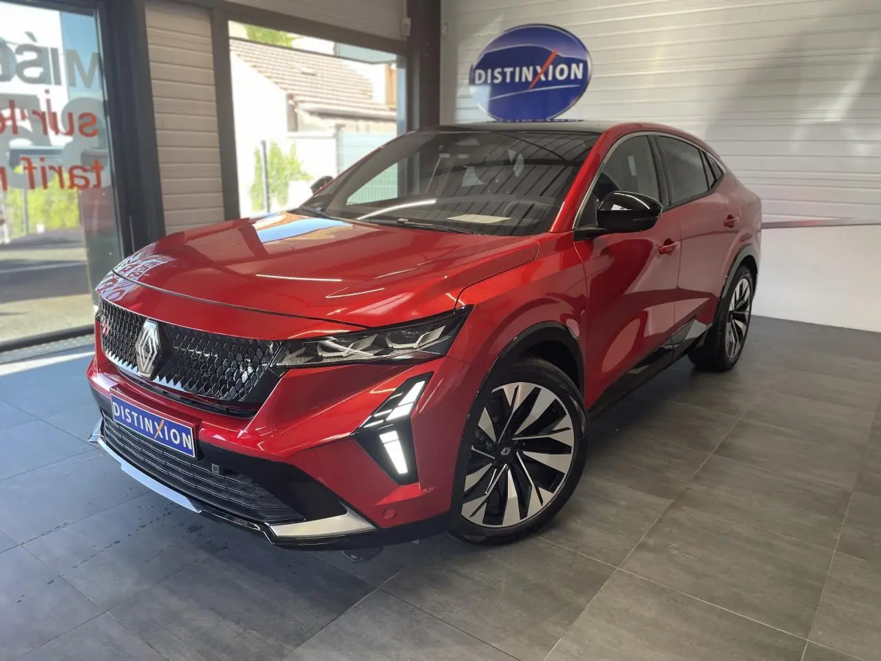 Renault Rafale rouge avec toit noir, vue 3/4 avant droit, feux LED en forme de flèche et jantes diamantées noires.