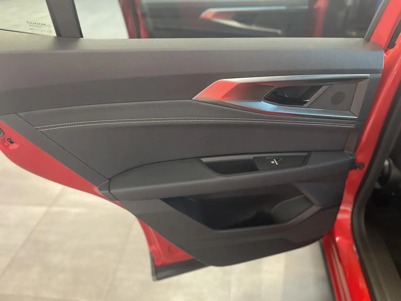 Vue intérieure de la porte avant gauche rouge du Renault Rafale 2025 avec garniture noire et surpiqûres blanches.