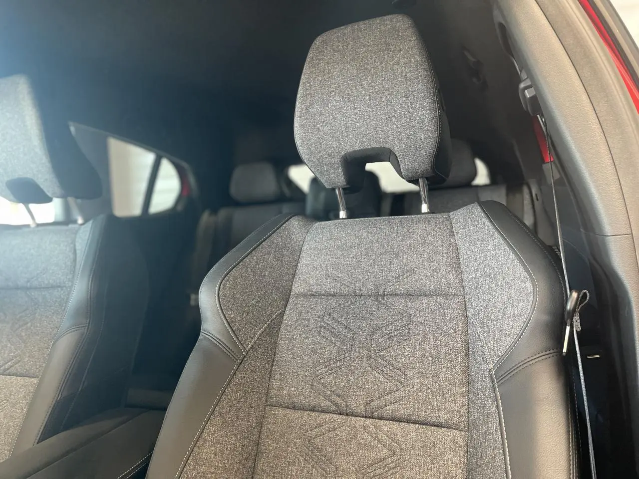 Gros plan sur le siège avant droit gris textile et cuir noir avec surpiqûres, intérieur du Renault Rafale rouge visible.