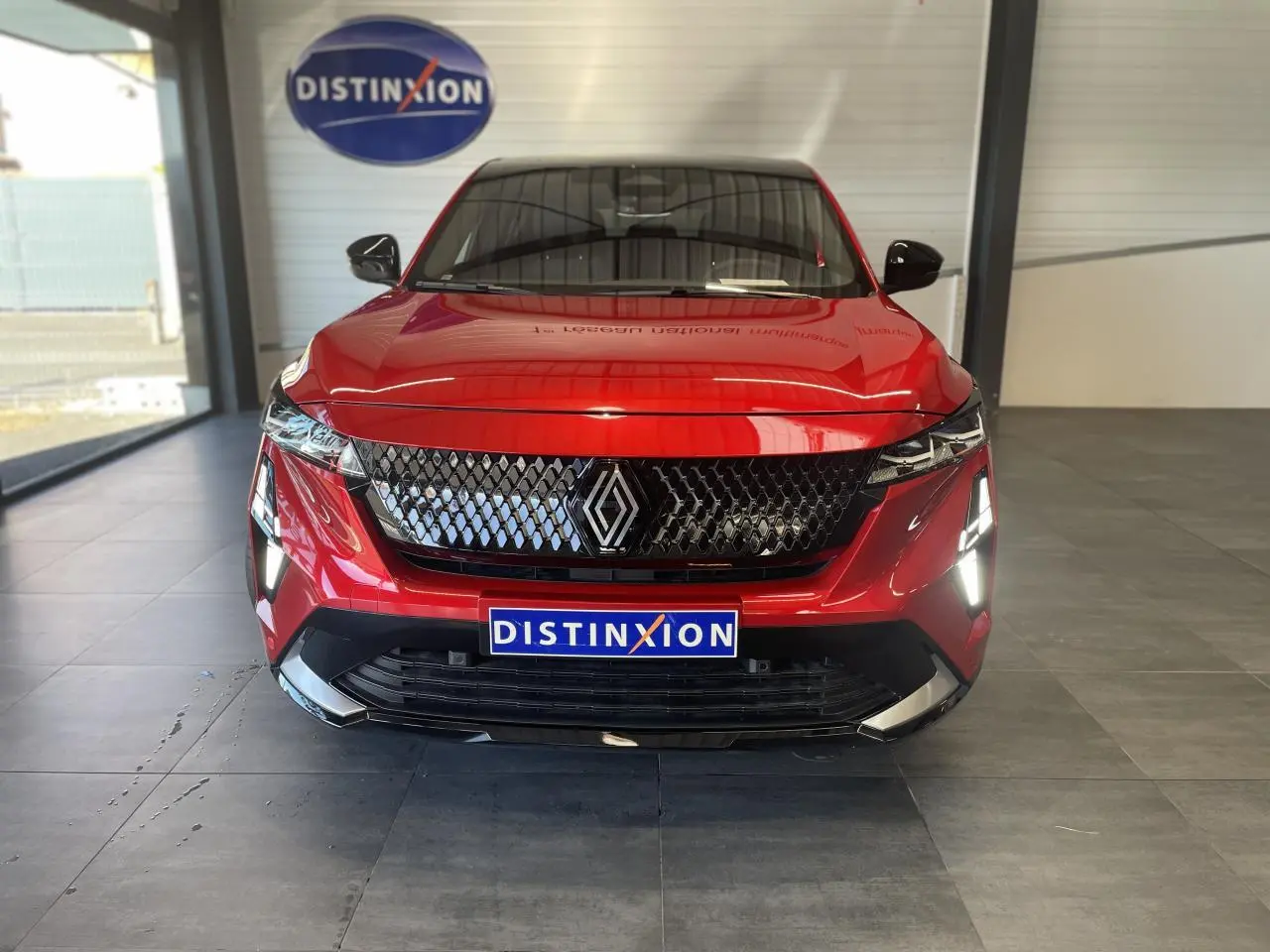 Vue de face du Renault Rafale rouge à toit noir avec calandre 3D et feux LED allumés en showroom.