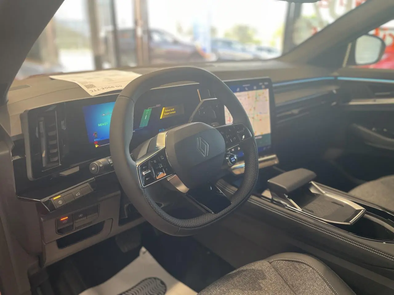 Vue intérieure côté conducteur du Renault Rafale 2025, volant noir avec logo Renault et écran tactile central lumineux.