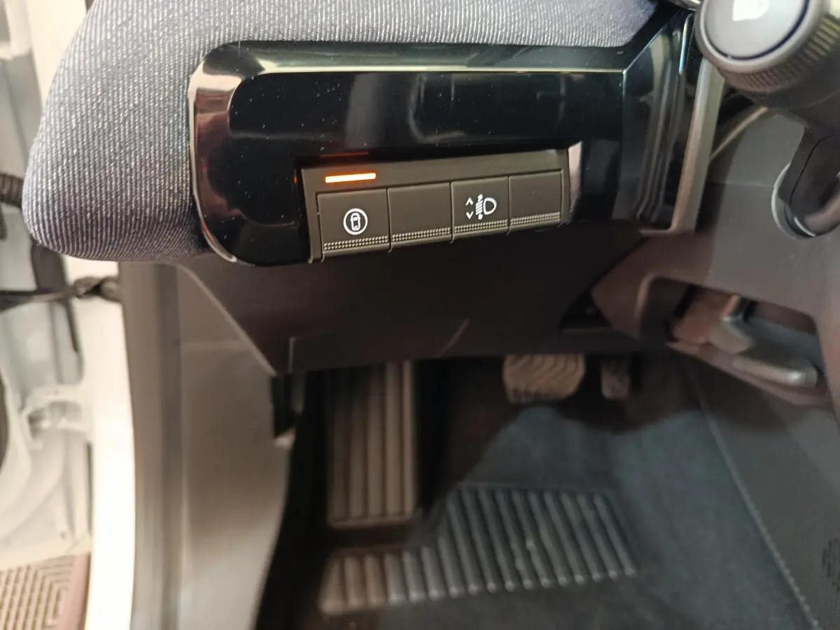 Vue intérieure côté conducteur de la Renault R5 Techno blanche 2025, avec commandes de réglage des phares et verrouillage.