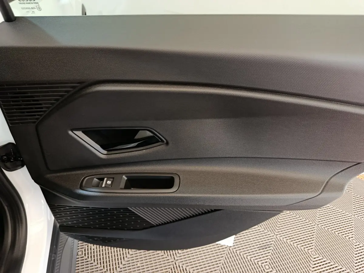 Vue rapprochée de la porte intérieure côté gauche blanche de la Renault R5 Techno 150 ch avec poignée noire et commande de vitre.