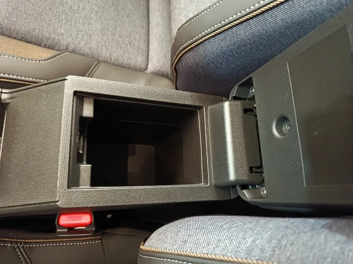 Vue plongeante sur la console centrale ouverte de la Renault R5 Techno 150 ch blanc, avec accoudoir et siège tissu gris.