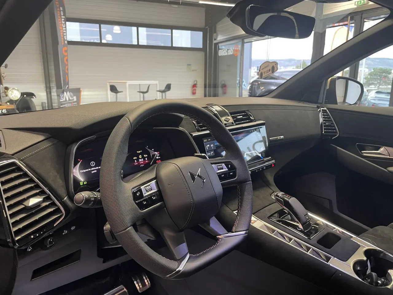 Vue intérieure avant droite du DS7 Crossback 2026, volant cuir perforé noir avec surpiqûres, tableau de bord et console centrale élégants.