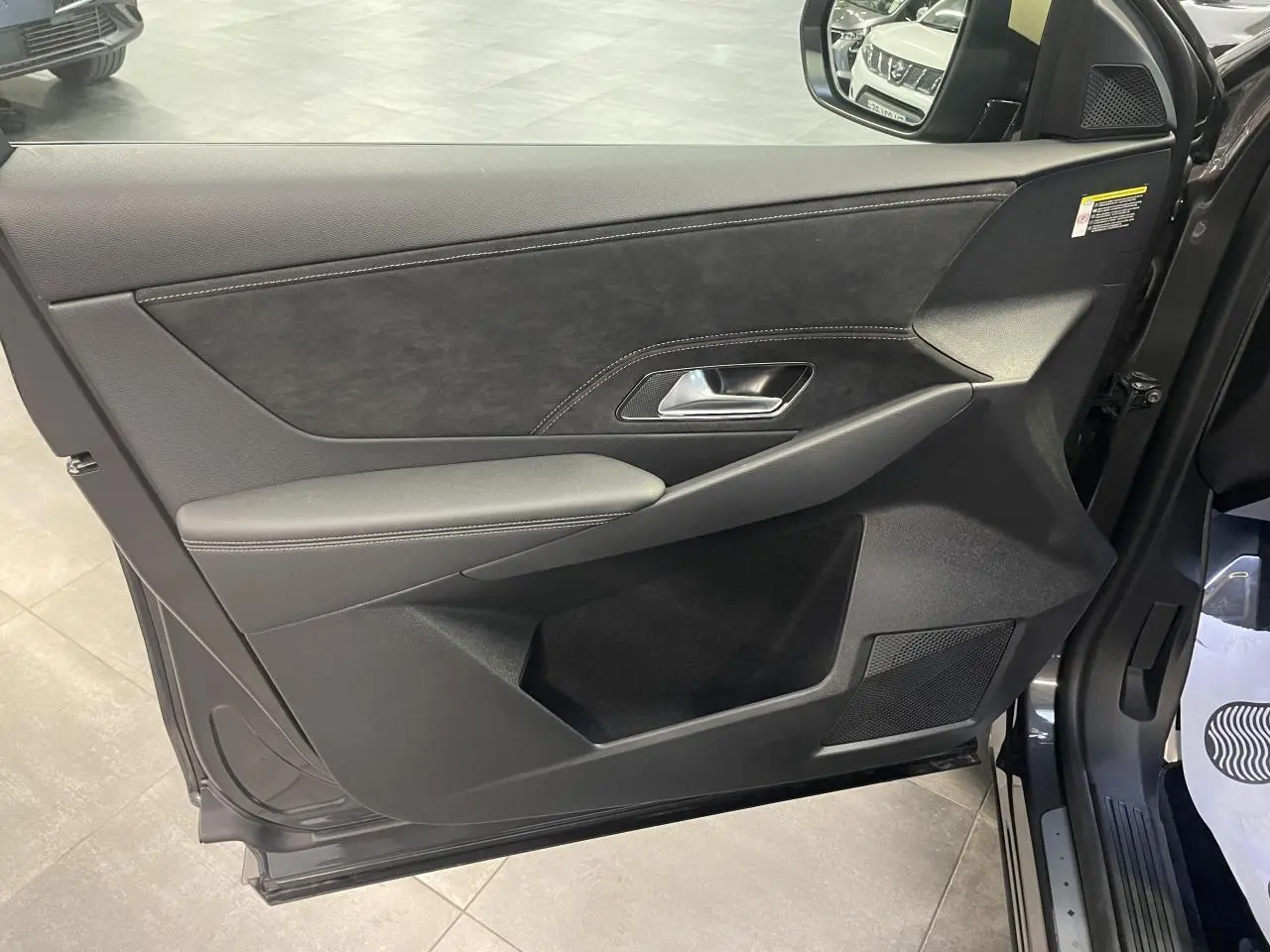 Vue intérieure côté gauche de la porte avant gris titanium du DS7 Crossback avec garniture Alcantara et surpiqûres contrastées.