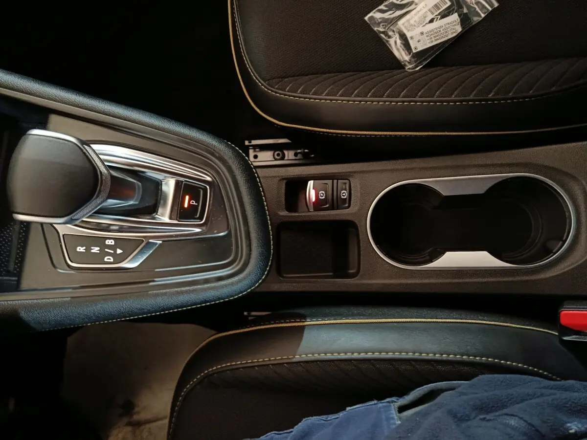 Vue plongeante sur la console centrale noire du Renault Symbioz avec levier de vitesse automatique et porte-gobelets.