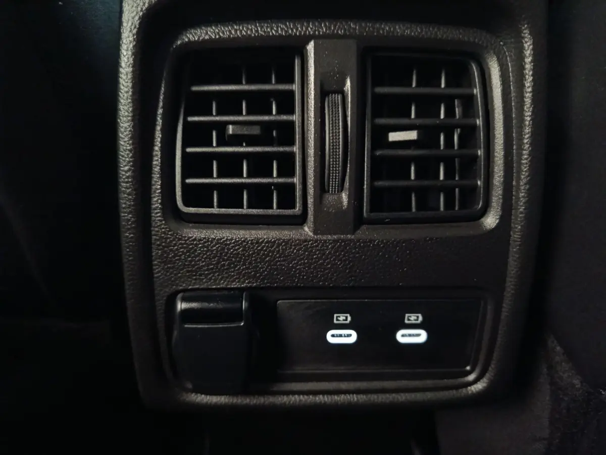 Vue rapprochée des prises USB et des aérateurs arrière noirs du Renault Symbioz Iconic E-Tech bleu 2025.