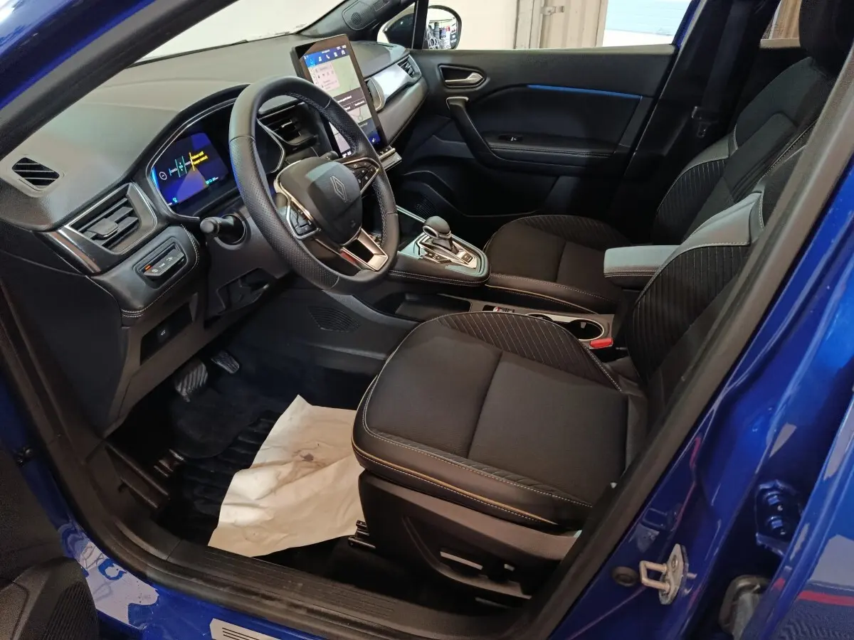 Vue intérieure côté conducteur de la Renault SYMBIOZ bleu, avec tableau de bord numérique et écran tactile central.