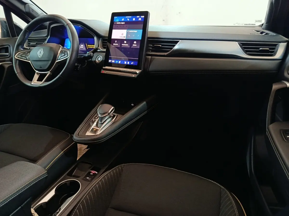 Vue intérieure côté conducteur du tableau de bord noir du Renault Symbioz avec écran tactile vertical et volant multifonctions.