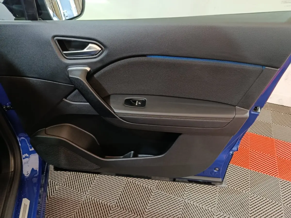 Vue intérieure de la porte avant gauche bleu Renault Symbioz 2025, avec poignée argentée et commande de fenêtre.